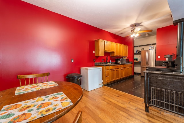 kitchen featuring dark wood-style flooring, dark countertops, a sink, stainless steel appliances, and a ceiling fan