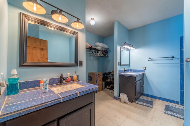 bathroom with baseboards, a sink, two vanities, and tile patterned floors