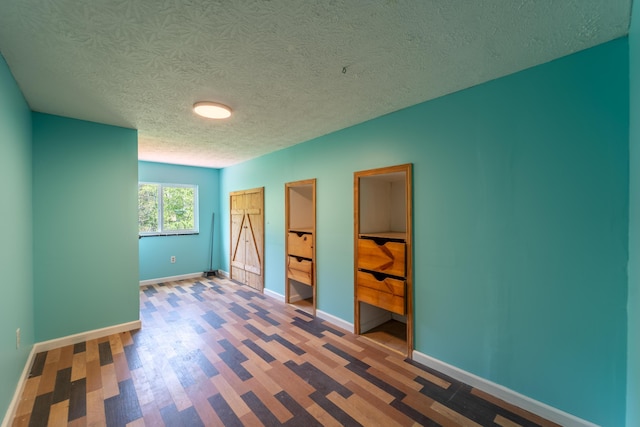 unfurnished bedroom featuring baseboards, a textured ceiling, and wood finished floors