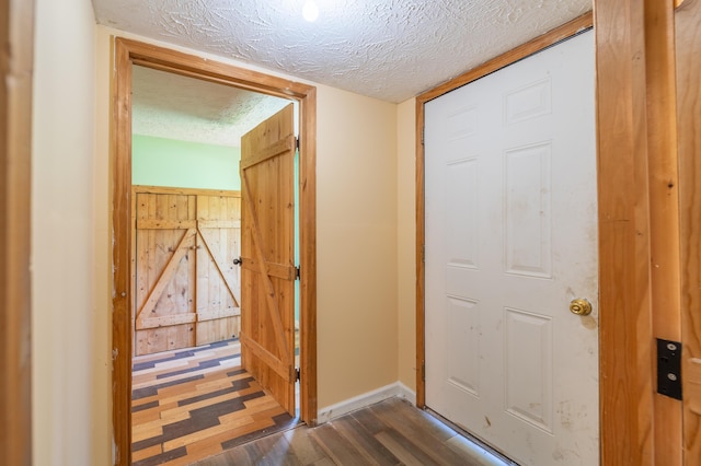 interior space with a textured ceiling, dark wood-style floors, and baseboards