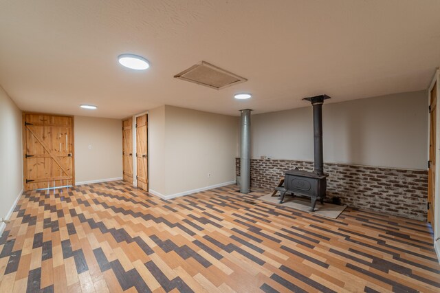 basement featuring carpet floors, a wood stove, baseboards, and recessed lighting