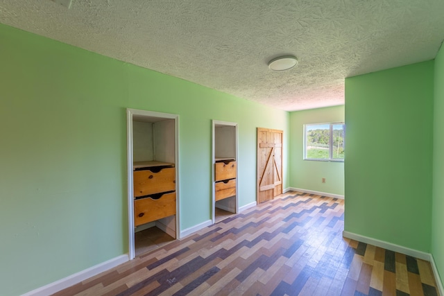 unfurnished bedroom with a textured ceiling, baseboards, and wood finished floors
