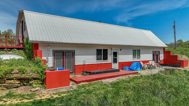 back of house with a lawn, a deck, and metal roof