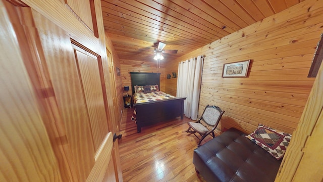bedroom with wooden walls, wood ceiling, a ceiling fan, and light wood-style flooring