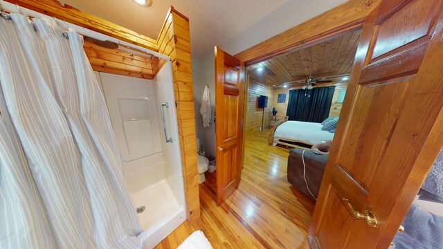 full bathroom featuring toilet, ceiling fan, a shower stall, and wood finished floors