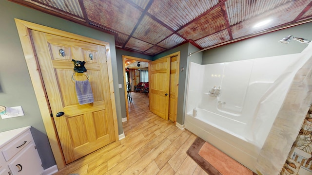 bathroom with shower / bath combination, baseboards, and hardwood / wood-style flooring