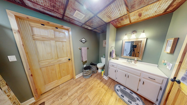 bathroom featuring visible vents, vanity, baseboards, toilet, and hardwood / wood-style floors