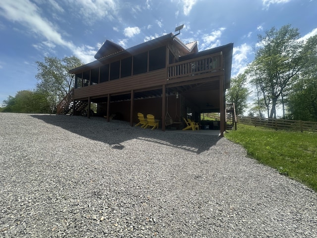 rear view of property with a sunroom, fence, stairs, and a deck