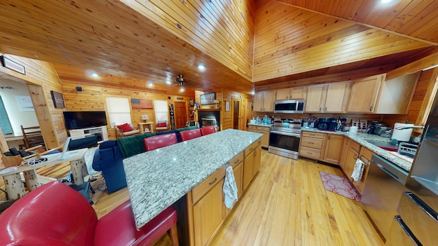 kitchen featuring appliances with stainless steel finishes, light wood-style floors, wood walls, wooden ceiling, and a kitchen island