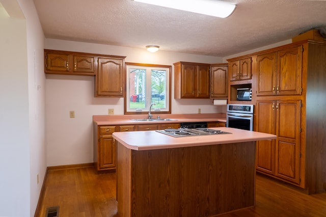 138 Hackett Pike, Richmond, KY 40475 - kitchen featuring appliances with stainless steel finishes, wood finished floors, brown cabinetry, and a sink