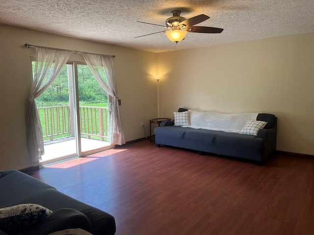 living room with a textured ceiling, ceiling fan, wood finished floors, and baseboards