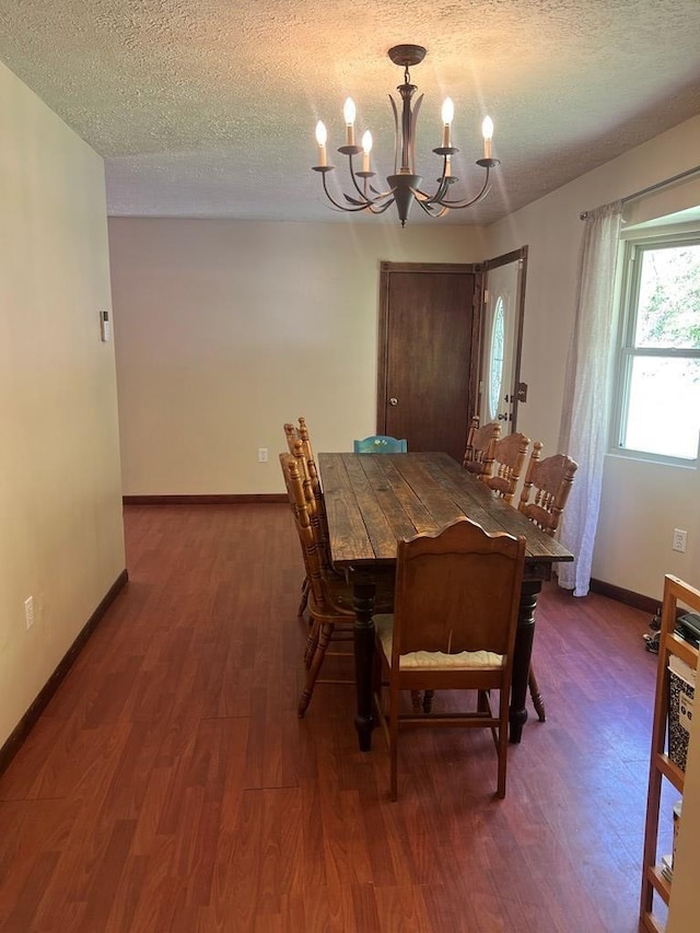 dining area featuring a textured ceiling, wood finished floors, a chandelier, and baseboards
