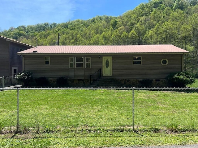 view of front facade with fence, metal roof, entry steps, and a view of trees