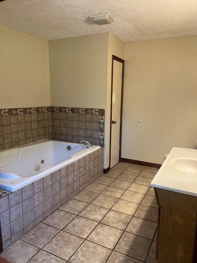 bathroom featuring a textured ceiling, visible vents, a jetted tub, tile patterned floors, and vanity