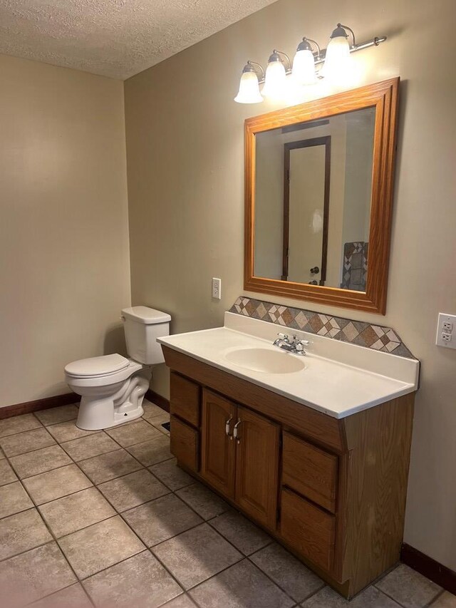 half bath with vanity, toilet, tile patterned flooring, and baseboards