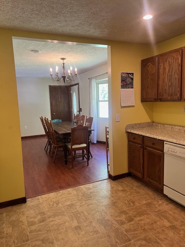 dining area with a textured ceiling, a chandelier, and baseboards