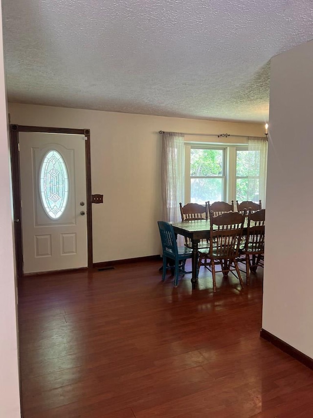 dining room featuring a textured ceiling, wood finished floors, and baseboards