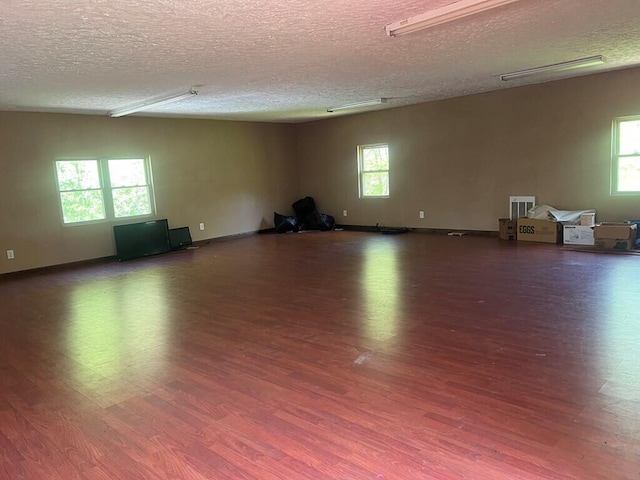 unfurnished room featuring baseboards, wood finished floors, and a textured ceiling