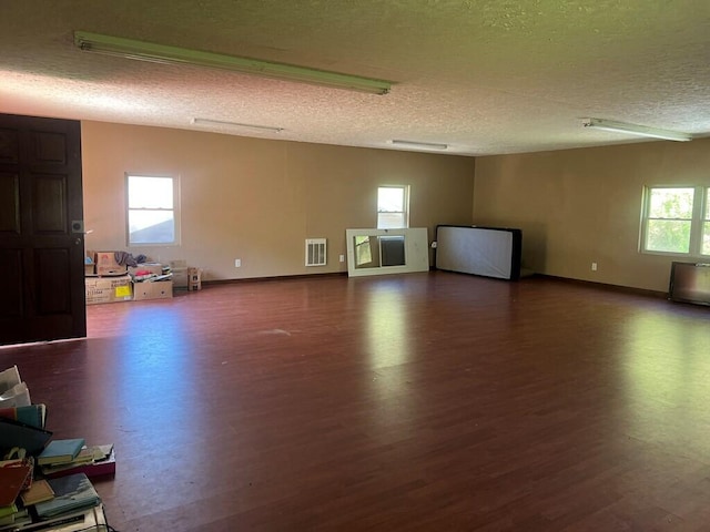 unfurnished room featuring a textured ceiling, wood finished floors, visible vents, and baseboards
