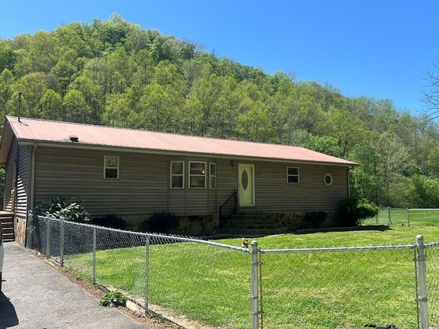view of front of house featuring a front yard, entry steps, fence private yard, and a view of trees