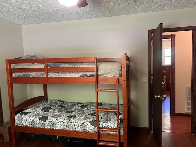 bedroom featuring a textured ceiling, wood finished floors, and baseboards