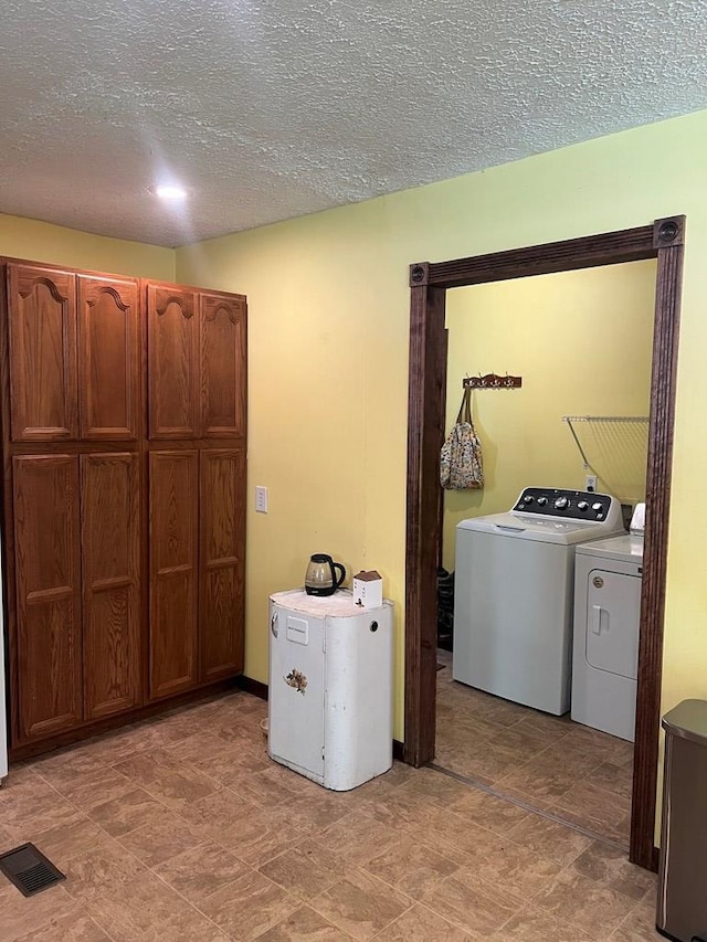 laundry room with independent washer and dryer, laundry area, visible vents, stone finish floor, and a textured ceiling