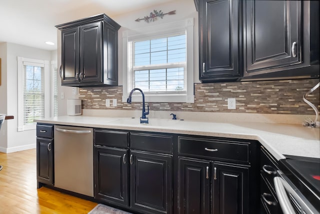 kitchen with a healthy amount of sunlight, stainless steel dishwasher, dark cabinets, and a sink