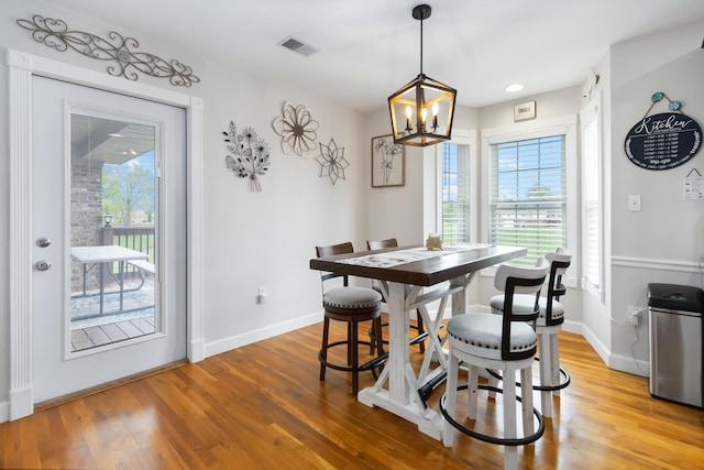 dining room with light wood finished floors, visible vents, a chandelier, and baseboards
