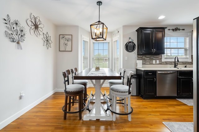 dining space featuring baseboards, recessed lighting, a notable chandelier, and light wood-style floors