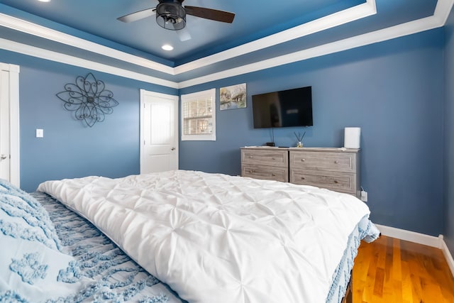 bedroom with recessed lighting, ceiling fan, a raised ceiling, baseboards, and wood finished floors