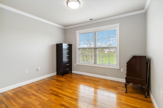 unfurnished room featuring light wood-style floors, crown molding, visible vents, and baseboards