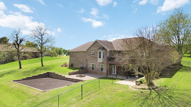 rear view of property featuring a patio, an outdoor fire pit, a fenced backyard, a lawn, and brick siding