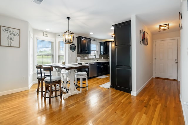 kitchen featuring baseboards, dishwasher, light countertops, and dark cabinetry