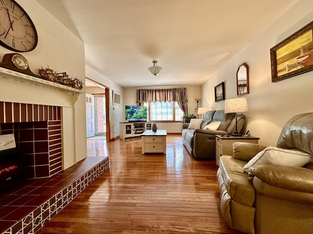 living room with wood-type flooring and a tiled fireplace
