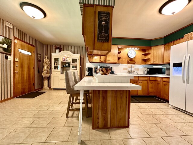 428 N Main St, Mckee, KY 40447 - kitchen featuring white refrigerator with ice dispenser, tile countertops, open shelves, black microwave, and brown cabinets
