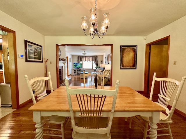 dining space with baseboards, a chandelier, and hardwood / wood-style flooring