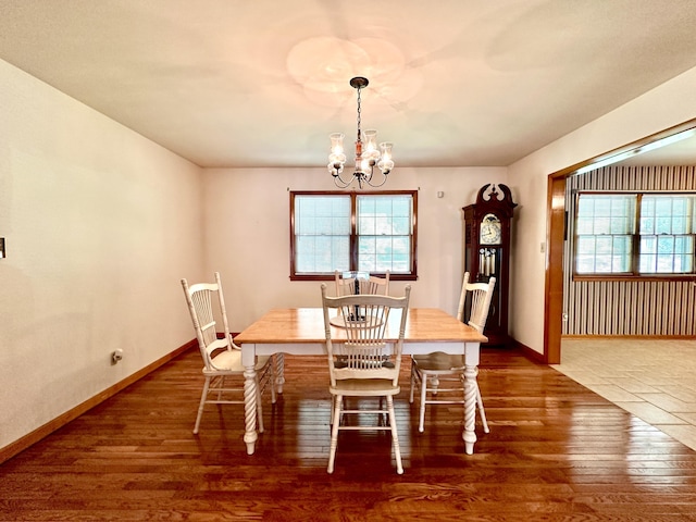 dining space featuring baseboards, a chandelier, plenty of natural light, and wood finished floors