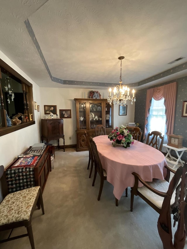 dining room with a textured ceiling, light colored carpet, baseboards, a notable chandelier, and visible vents