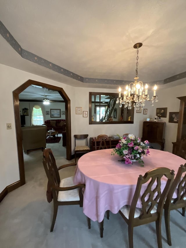 dining room with carpet, baseboards, arched walkways, and a notable chandelier