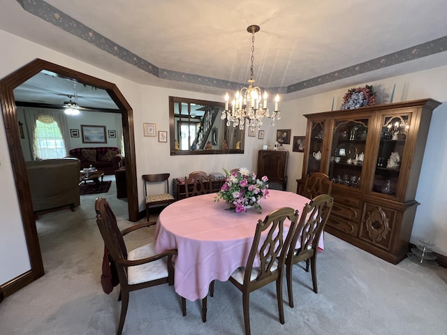 dining space featuring arched walkways, light carpet, and a notable chandelier