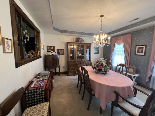 dining room featuring baseboards, visible vents, an inviting chandelier, light colored carpet, and a raised ceiling