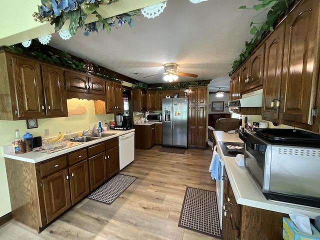 kitchen with a ceiling fan, a sink, white appliances, light wood finished floors, and under cabinet range hood