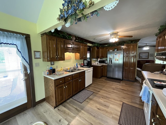 kitchen featuring light countertops, a ceiling fan, a sink, white appliances, and light wood-type flooring