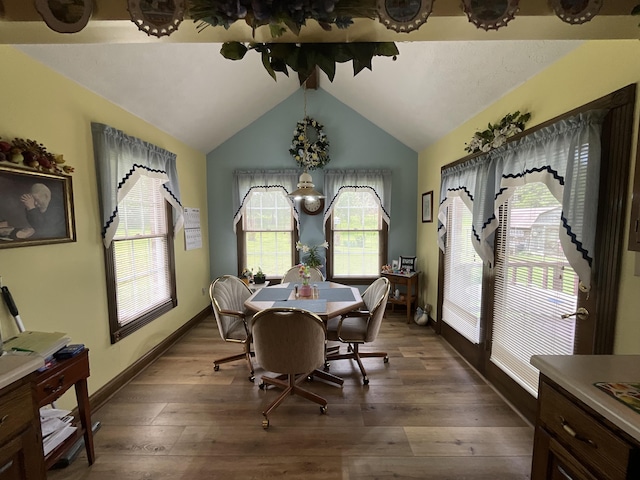dining space with lofted ceiling, wood finished floors, and baseboards