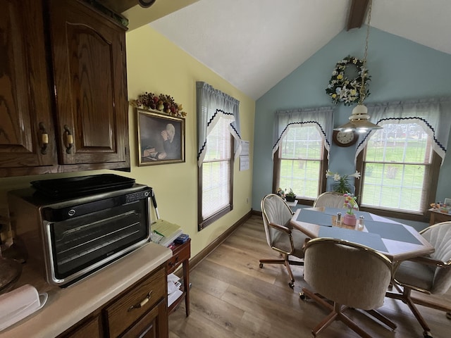 dining space featuring a toaster, lofted ceiling with beams, baseboards, and wood finished floors