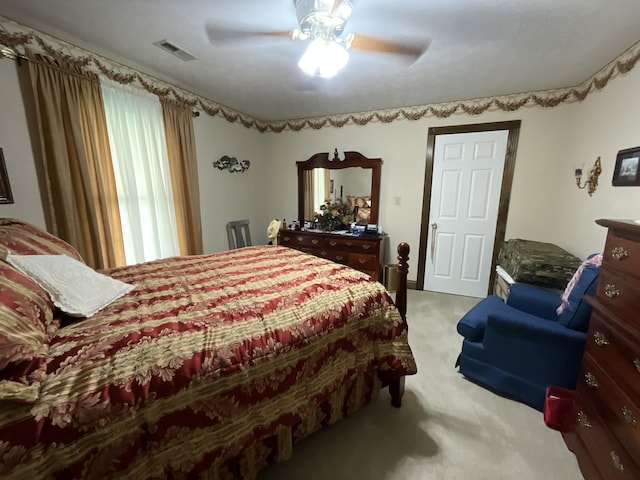 bedroom with light carpet, a ceiling fan, and visible vents