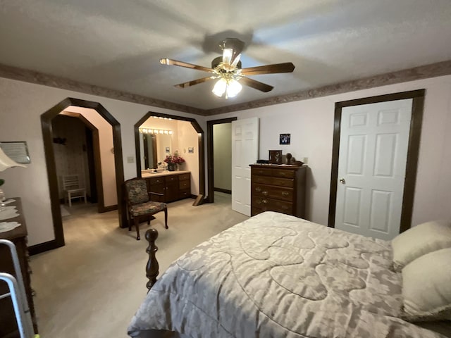 bedroom with ceiling fan, arched walkways, light carpet, and baseboards