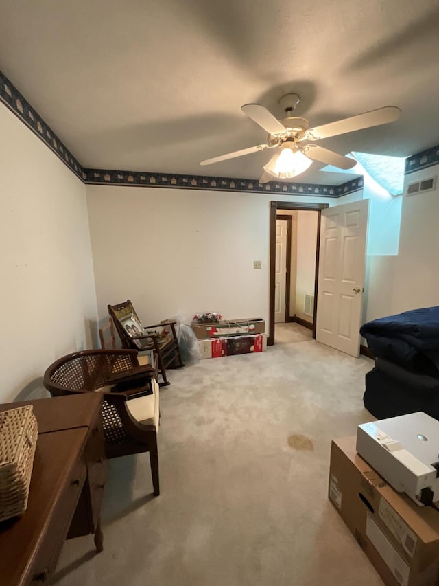 basement with visible vents, light colored carpet, and ceiling fan