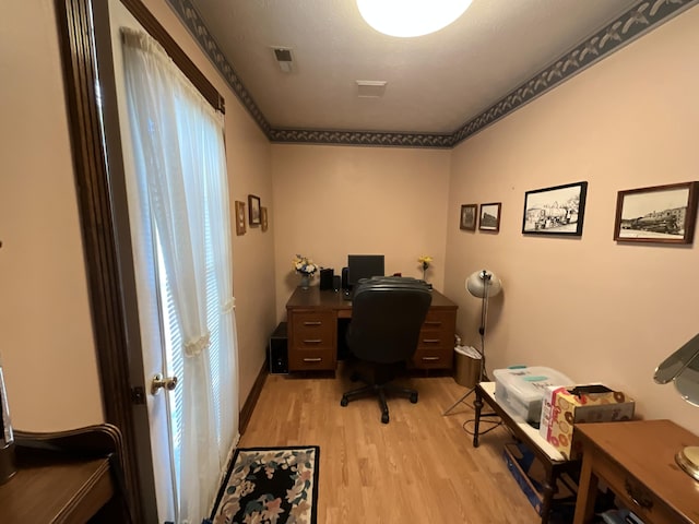home office with light wood-style flooring and visible vents