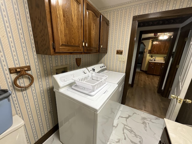 laundry room featuring wallpapered walls, wood finished floors, independent washer and dryer, and cabinet space